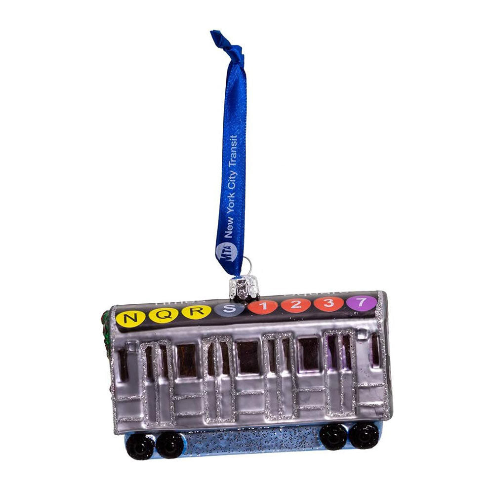The MTA NYC Glass Subway Car Ornament is a glittery, painted glass subway train with black wheels, colored circles labeled N, Q, R, S, 1, 2, 3, and 7 on top, and a blue “New York City Transit” ribbon for hanging.