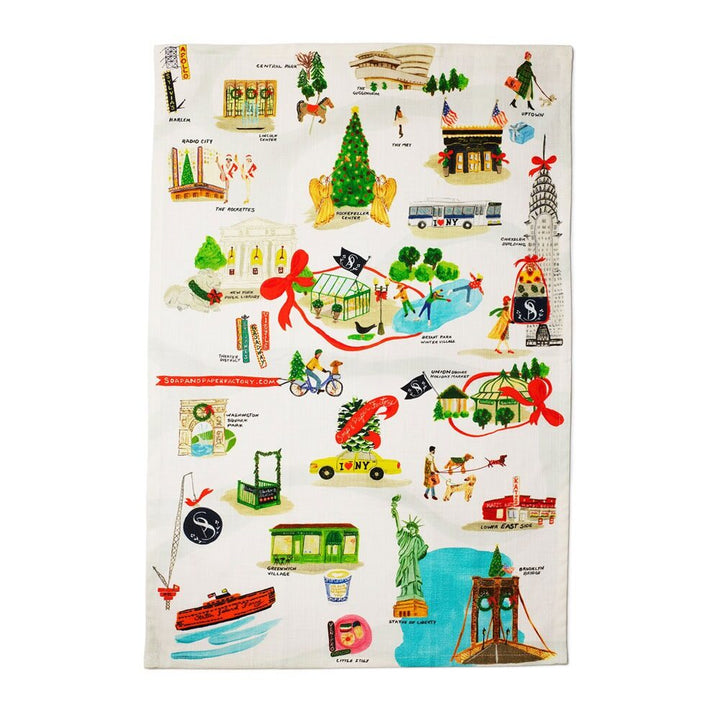 The Holiday in New York Tea Towel showcases vibrant illustrations of NYC landmarks like the Statue of Liberty, Central Park, Empire State Building, taxis, and subways with festive holiday decor. Alcohol-free and phthalate-free.