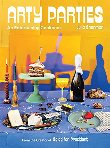 The Arty Parties Cookbook features a vibrant yellow and orange cover with a festive table set with cake, champagne, candles, fruit, and bread—perfect inspiration for home entertaining.