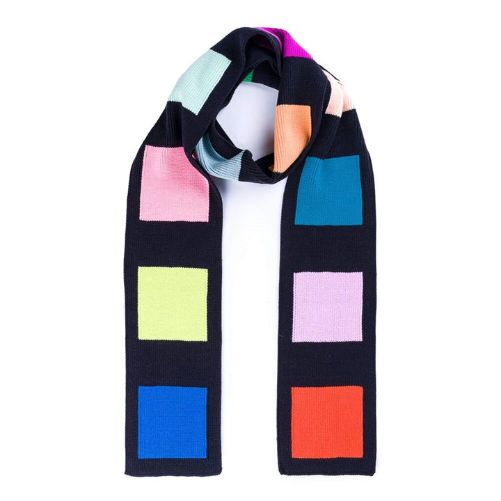 The Swatch Skinny Scarf is a soft black acrylic scarf with evenly spaced colorful squares—pink, blue, green, red, orange, and purple—on a white background. This long winter scarf is machine washable for easy care.