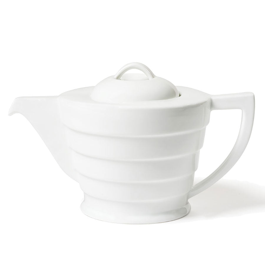 The Guggenheim Spiral Teapot is a modern white ceramic piece with a rounded, ribbed body and curved handle, echoing Mid-century Modern style. Its fitted lid has a loop handle, making it a standout for any tea collection.