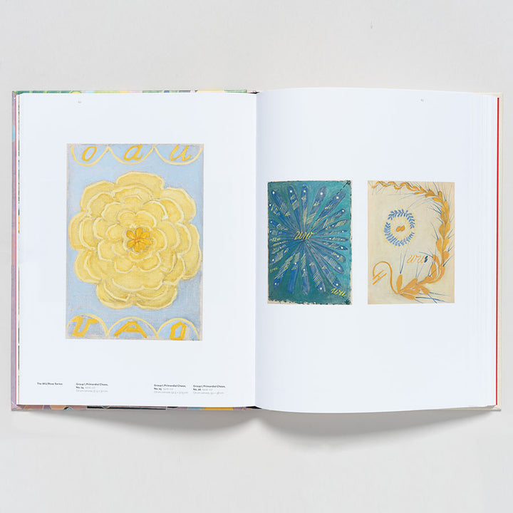 An open book of "Hilma af Klint: Paintings for the Future" displays three modernist abstract floral illustrations: a large yellow flower on blue, a radial blue-green design, and a small blue spiral with grasses on cream.