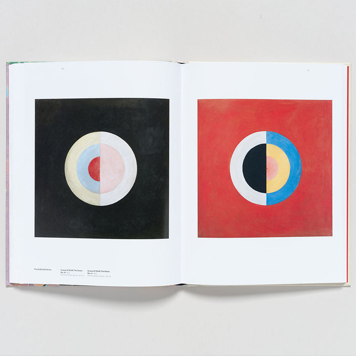 An open copy of "Hilma af Klint: Paintings for the Future" shows two abstract works—muted pastel circles on black on the left and a vibrant modernist piece with a bright red background on the right.