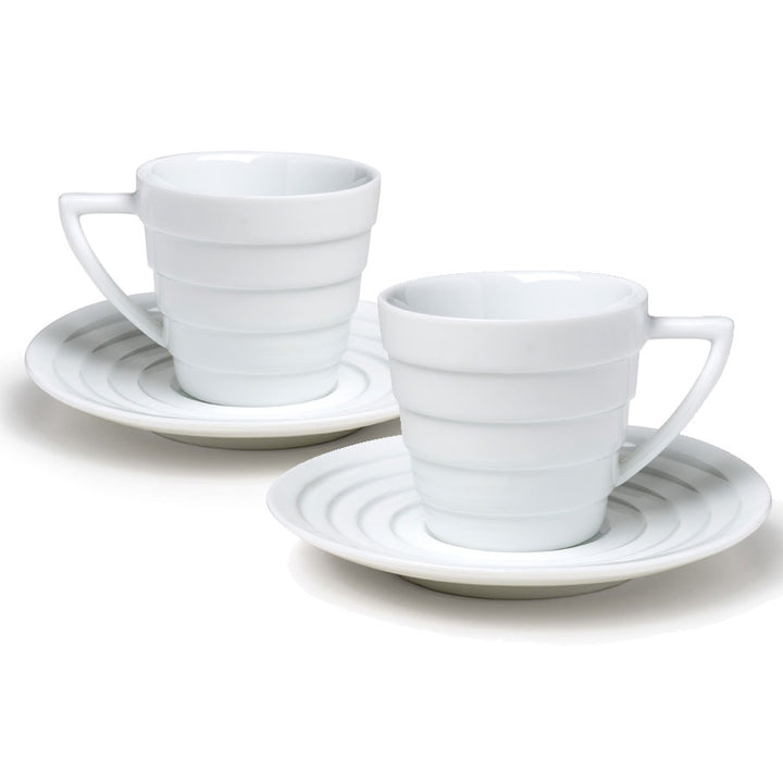The Guggenheim Spiral Espresso Cup Set features two white porcelain Mid-century Modern cups with handles, each on a matching saucer decorated with concentric circles, displayed against a white background.