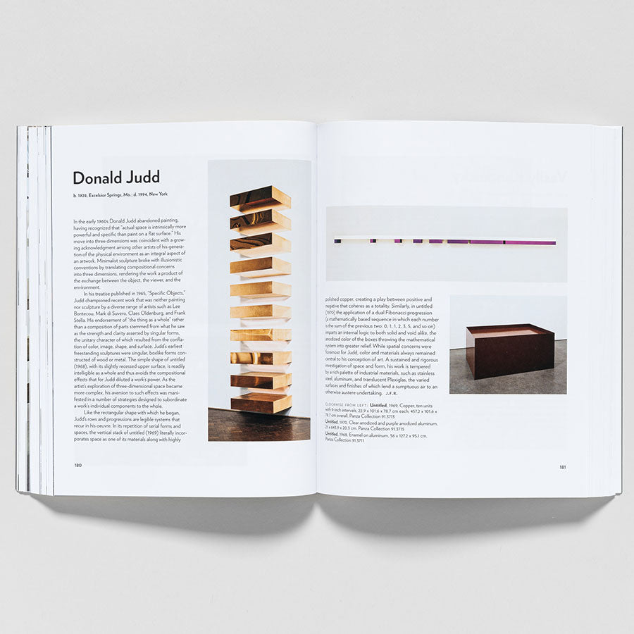 An open copy of "Guggenheim Museum Collection: A to Z (revised edition)" shows a Donald Judd spread with text and a photo of a stacked wooden sculpture on the left and minimalist wall installation and box sculpture on the right.