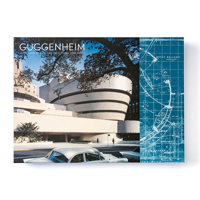 The Frank Lloyd Wright Guggenheim 2-sided 500 Piece Puzzle features a book cover design with the museum's iconic circular architecture, a large tree, vintage cars, blueprint accents, and "Guggenheim" at the top left.