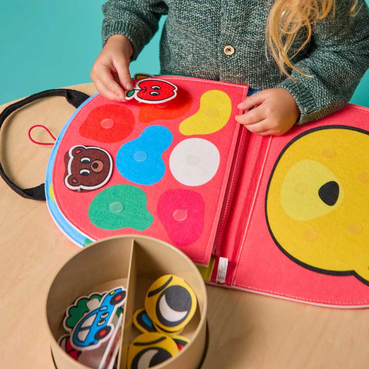 A child builds cognitive skills with the Guggenheim Museum Rainbow Montessori Play Kit’s sensory-rich felt activity book.