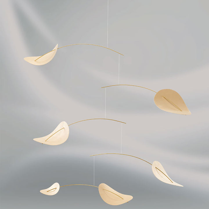 The Drifting Clouds Mobile by Flensted features five curved, light-colored elements suspended on thin wires, creating a delicate floating effect against a soft gray background.