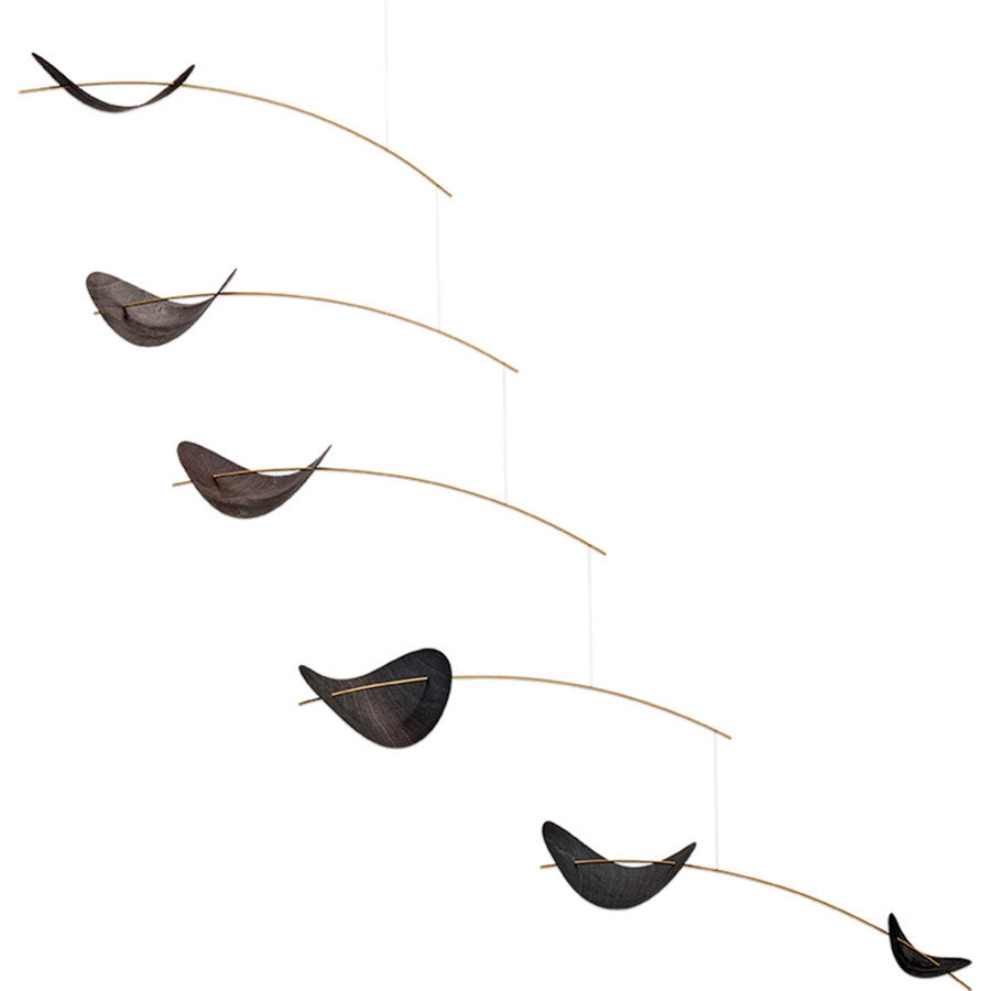 The Black Drifting Clouds Mobile by Flensted features five curved black elements suspended from thin golden rods, arranged diagonally from top left to bottom right against a white background, inspired by Danish design.