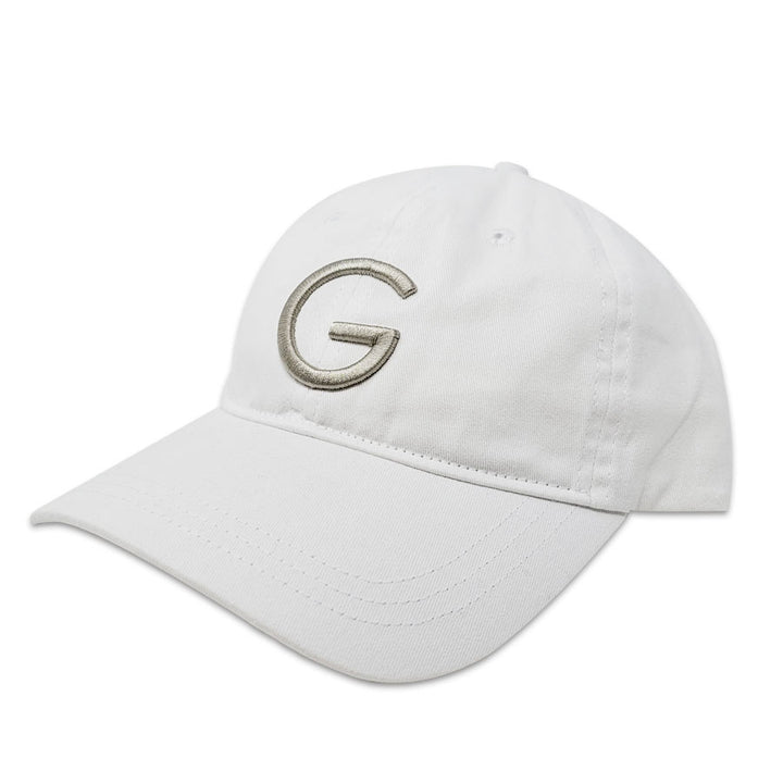 The Guggenheim "G" White Cap is a cotton baseball cap with an adjustable fit, curved brim, and a large gray embroidered "G" on the front, inspired by iconic Guggenheim style.