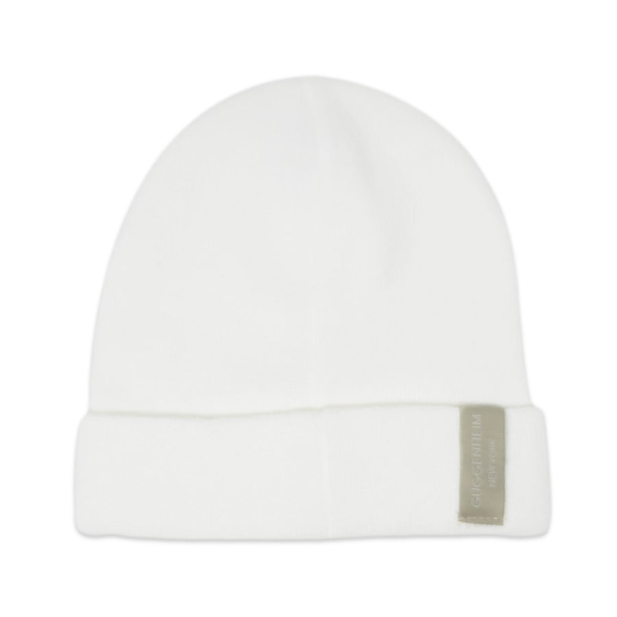 The Guggenheim White Beanie features a folded brim and a small rectangular gray tag on the front right side, making it perfect for winter fashion.