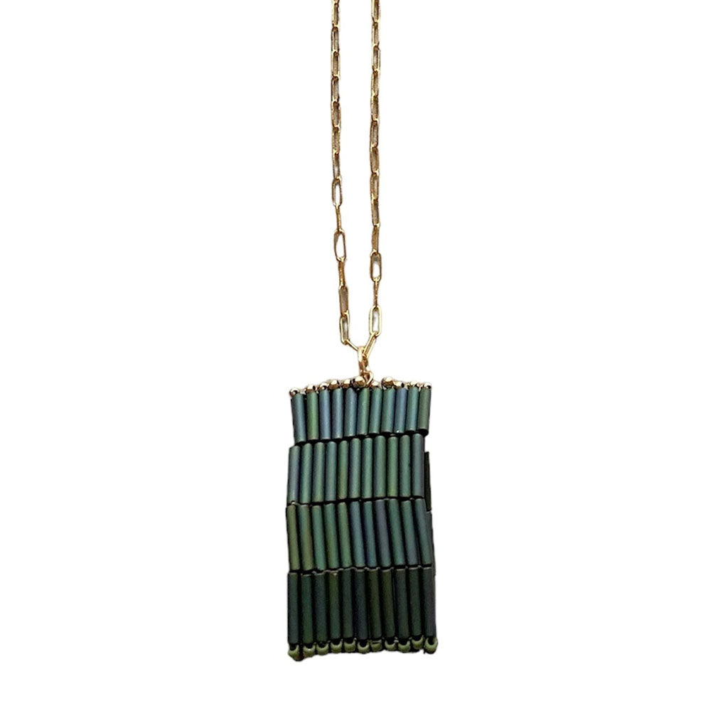 The Trecy Bleich Rice Stack Necklace Moss features a gold chain and rectangular pendant with three rows of vertically stacked, dark green cylindrical beads—an elegant piece from our handcrafted jewelry Rice collection.