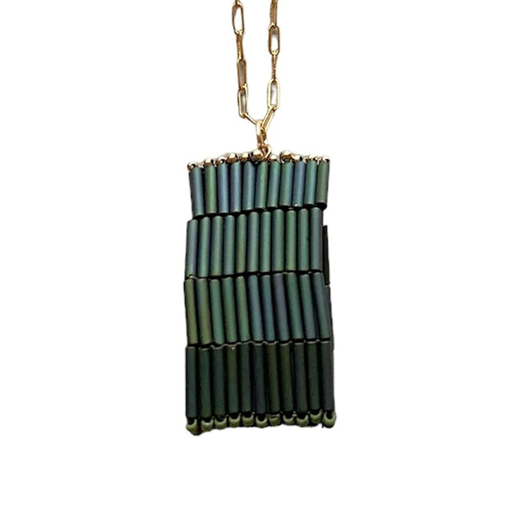 The Trecy Bleich Rice Stack Necklace Moss showcases iridescent green tube beads in three uneven, vertical rows on a gold elongated-link chain—a handcrafted piece from our Rice collection.