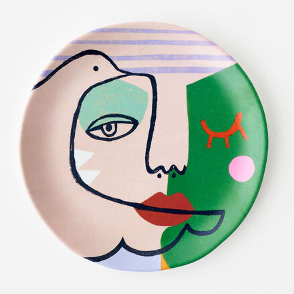 The Pablo Picasso Melamine Plate features an abstract face with bold lines and colorful shapes in green, pink, and beige—one eye open, one closed. Crafted from melamine, it's perfect for adding artful flair to your dining experience.