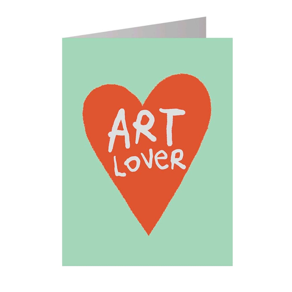 The Art Lover Notecard features a large red heart on a light green background with "ART LOVER" in white, hand-drawn letters inside the heart. Inspired by contemporary artists. The card is shown partially open.