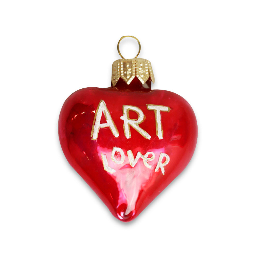 The Art Lover Ornament is a shiny red heart-shaped mini blown glass piece with a gold cap and "ART LOVER" in gold on the front—ideal for holiday decor or as a special keepsake from Humberto Cruz.
