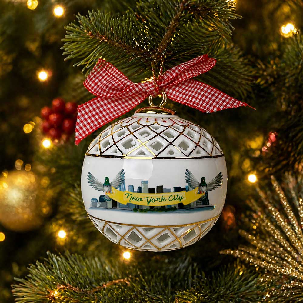 Guggenheim Museum NYC Sphere Ornament with Bow shines on a lit, festive tree, gold accents and red bow gleaming.