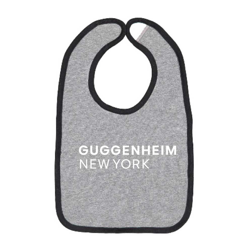 The Guggenheim New York Baby Bib is gray with black trim and white text on the front—a stylish museum accessory for your little one.