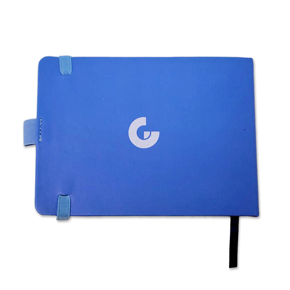 The Stella Harran II Notebook is a blue journal featuring a centered white G logo, two light blue corner bands, a side tab, and a black ribbon bookmark—ideal for stylish note-taking.