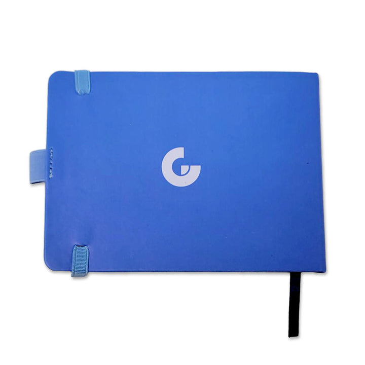 The Stella Harran II Notebook is a blue journal featuring a centered white G logo, two light blue corner bands, a side tab, and a black ribbon bookmark—ideal for stylish note-taking.