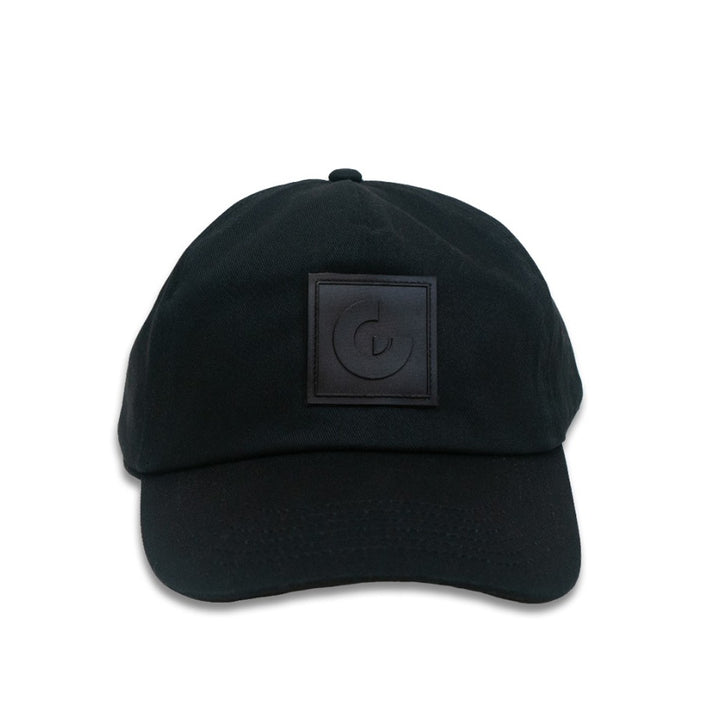 The Guggenheim Constellation Cap New York features a minimalist black design with a square patch and raised G logo on the front. This adjustable cotton cap combines style and comfort, shown here against a white background.