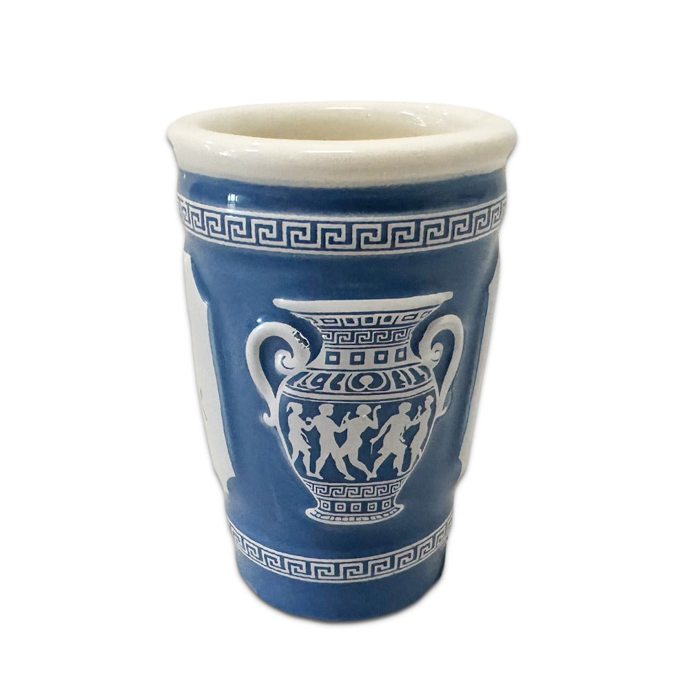 The 3D NYC Coffee Cup Shot Glass, 2 oz, mimics a classic NYC coffee cup in blue and white with Greek-inspired patterns and iconic motifs. The rim and base have geometric borders. Hand wash only to maintain its detailed design.