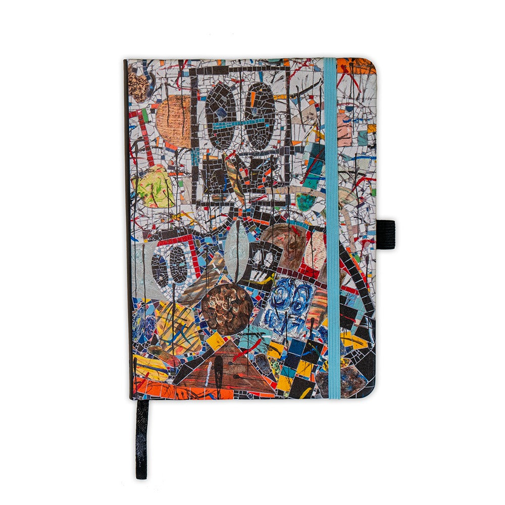 The Rashid Johnson Broken Man Vegan Leather Journal features a colorful abstract cover with geometric shapes and collage elements, secured by a light blue elastic band and includes a black pen holder on the side.