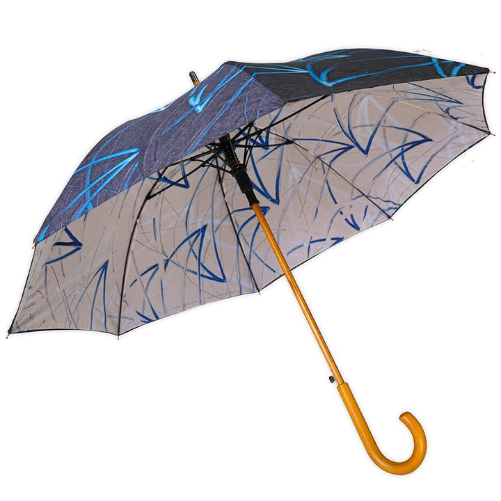 The Rashid Johnson Dual Sided Stick Umbrella, Untitled Seascape Drawing, features a wooden curved handle and a canopy with an artistic blue and black abstract pattern, bringing creativity to rainy days.
