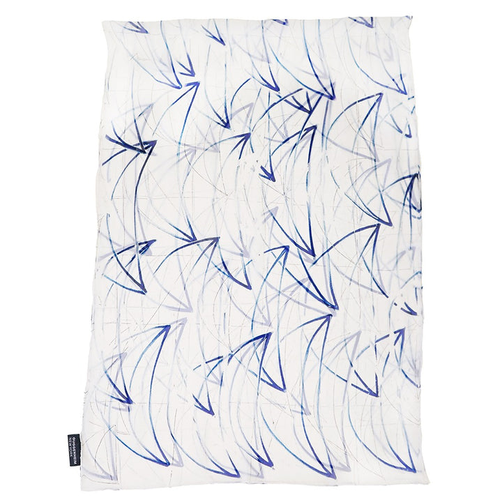 The Rashid Johnson Scarf, "Seascape," features white silk chiffon with abstract navy and light blue arrow-like lines in a dynamic, swirling pattern. Inspired by seascapes, it includes a small black tag on the bottom left edge.