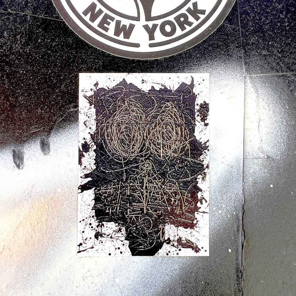 The Rashid Johnson Untitled Anxious Man Sticker, sized 2.5" x 3.5", features an abstract dark face with scribbled eyes and mouth, set on a glossy black and white background below a partial circular "New York" sign.
