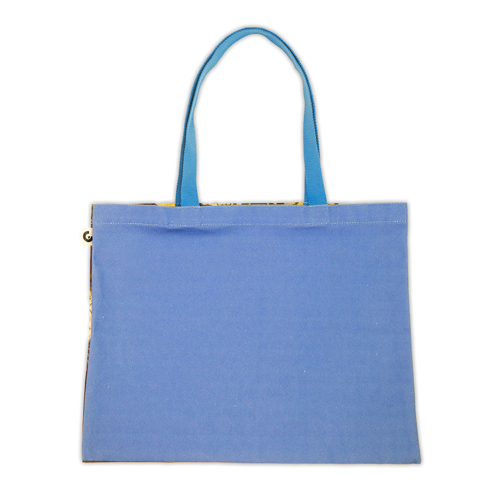 The Guggenheim Beatriz Milhazes Tote Bag, In Albis, is a rectangular light blue canvas tote with matching handles and a minimalist design—ideal for art lovers—shown against a white background.