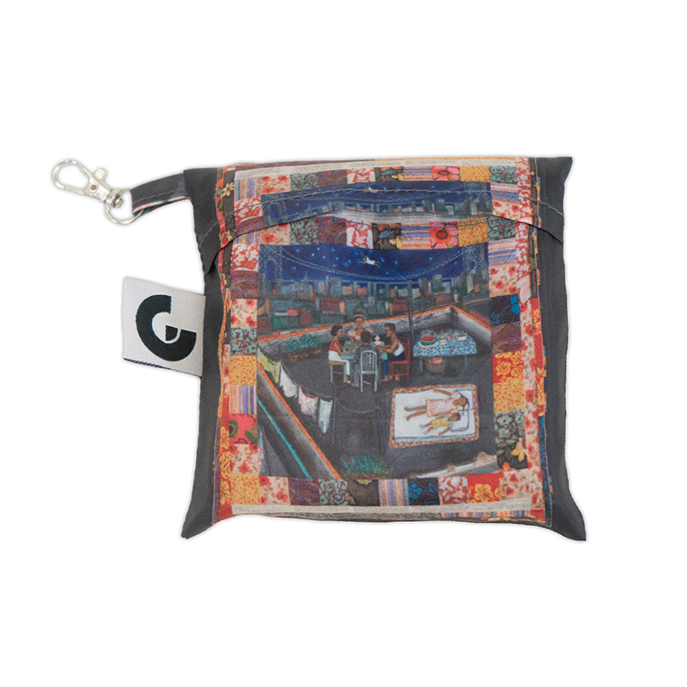 The Faith Ringgold Tar Beach Foldable Tote Bag is made from RPET recycled material and features a zipper, keychain clip, bold G logo tag, patchwork border, and artwork of people dining on a rooftop at night.