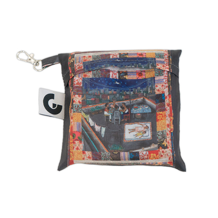 The Faith Ringgold Tar Beach Foldable Tote Bag is made from RPET recycled material and features a zipper, keychain clip, bold G logo tag, patchwork border, and artwork of people dining on a rooftop at night.