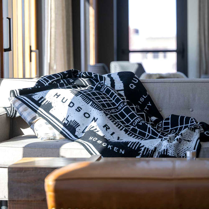 Guggenheim Museum New York City Map Wool Throw on a light gray couch in a sunlit living room.