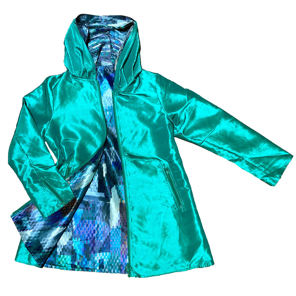 The Delaunay Window Reversible Jacket is a shiny turquoise women's zip-up hooded coat with zippered front pockets and a vibrant, pixelated blue and purple patterned lining, displayed on a white background.