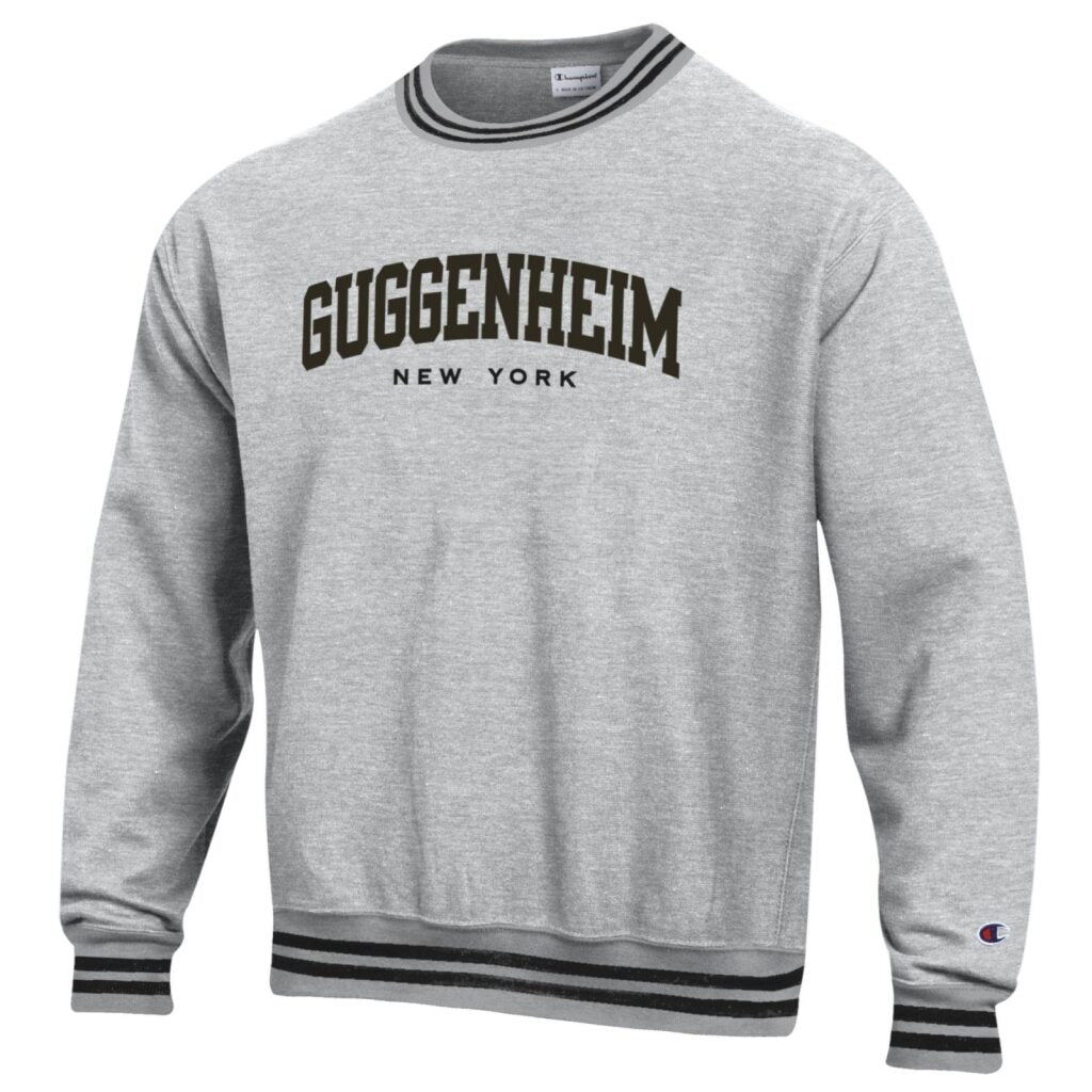 The Guggenheim Embroidered Striped Collegiate Sweatshirt is a gray unisex crewneck with black and white striped cuffs and hem, featuring GUGGENHEIM NEW YORK on the front. Made from a soft cotton-polyester blend and machine washable.