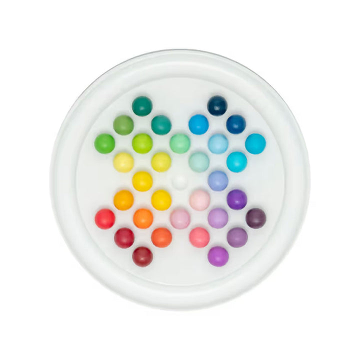 A white tray by Guggenheim Museum holds Gradient Solitaire’s hand-painted balls in a color theory-inspired triangle.