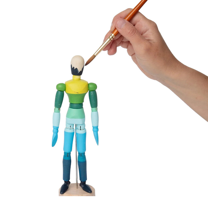 A hand paints a Guggenheim Museum Paint and Pose Mannequin head, highlighting anatomy against a white background.