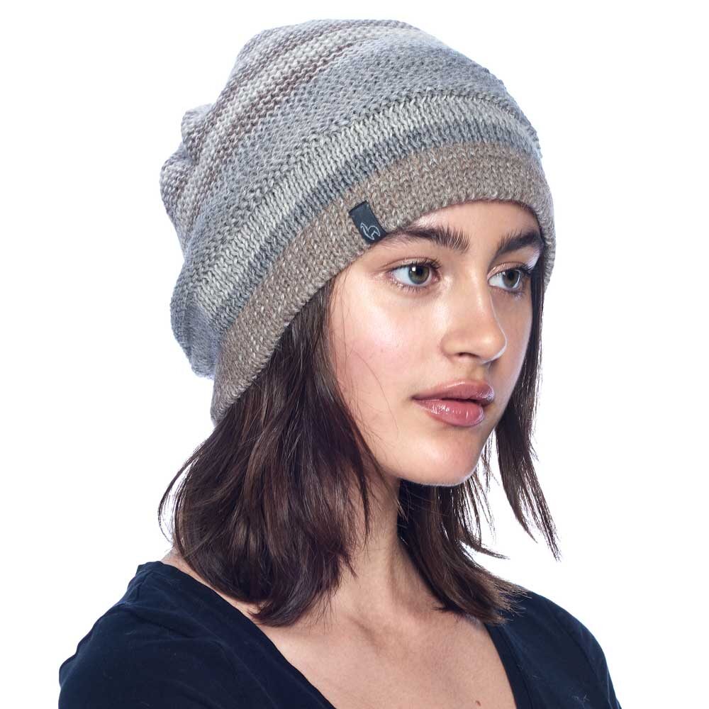 A young woman with shoulder-length brown hair wears the Colorado Alpaca Beanie in ivory, one size, made from soft baby alpaca. She pairs it with a black top and looks slightly to the side against a plain white background.