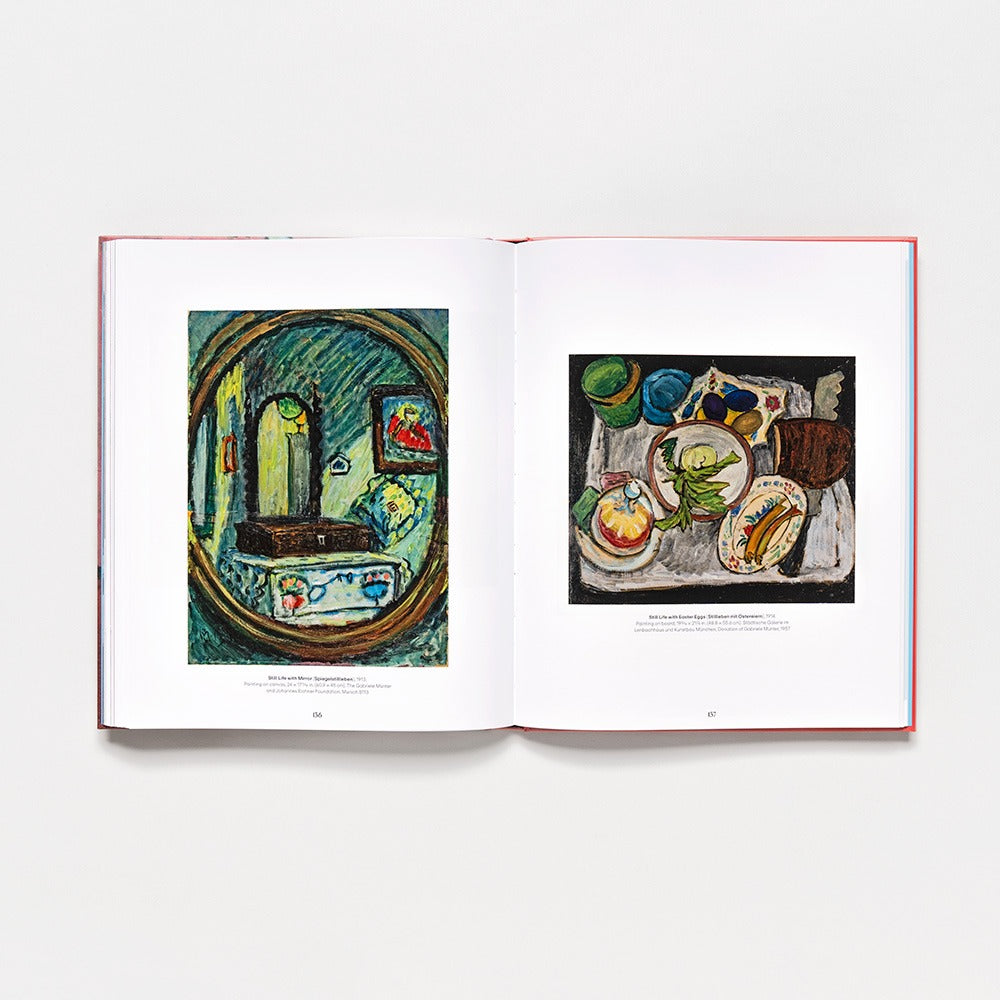 The hardcover book "Gabriele Münter: Contours of a World" opens to two vibrant paintings: on the left, a room with mirror, table, and chair; on the right, a still life with plates of food and green cups—an inspiring 2025 vision.