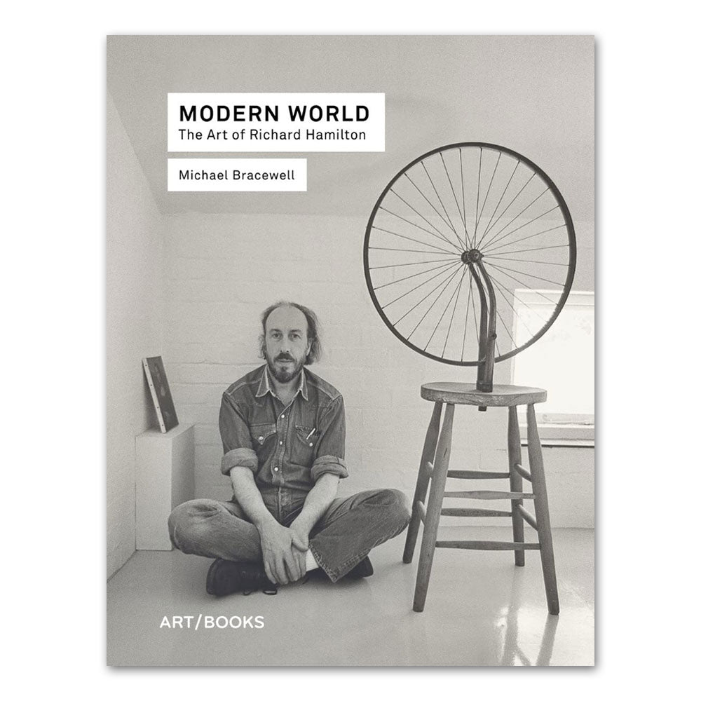 A man sits cross-legged by a Pop art chair with a bicycle wheel on the cover of Guggenheim’s *Modern World: The Art of Richard Hamilton*.