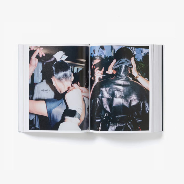 An open book reveals a backstage photo from Alaïa by Seklaoui, featuring people adjusting hair and clothing—one in a shiny black jacket, another in an ALAÏA shirt—showcasing Pieter Mulier’s vision in this limited-edition release.