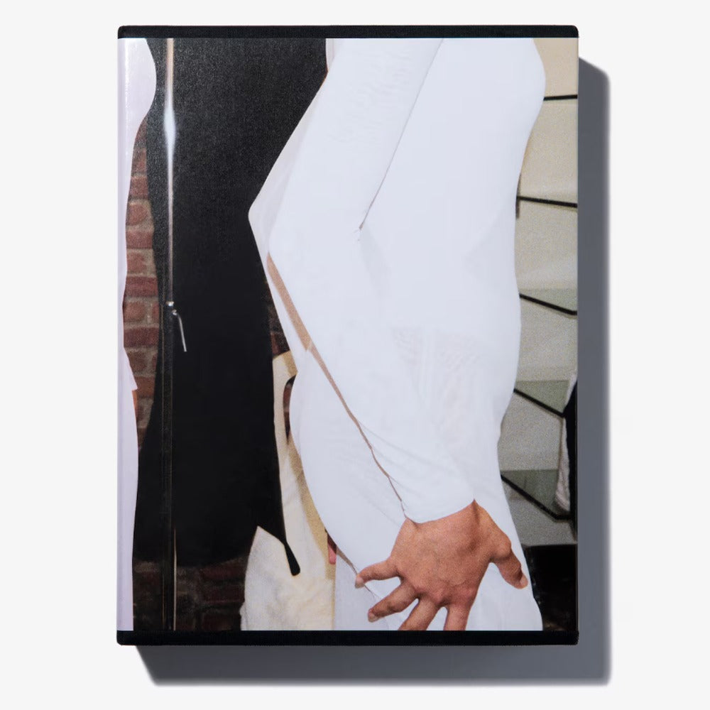 Alaïa by Seklaoui is a limited-edition book featuring a cover close-up of a person in white, hand on hip, posed amid geometric shapes—an elegant tribute to the iconic style.