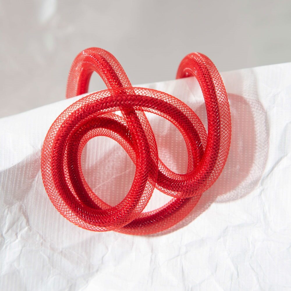 Red mesh hair tie on a white fabric background