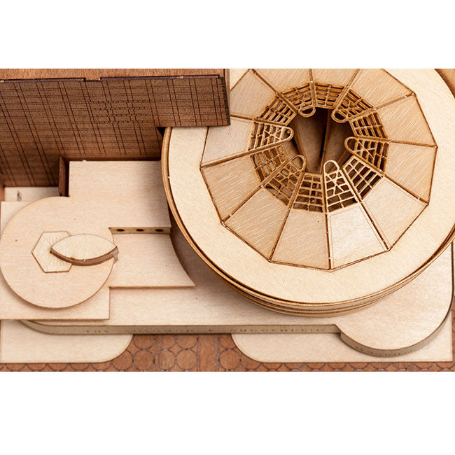 A close-up of the Guggenheim Architectural Model Kit shows its wooden construction, highlighting circular and geometric forms—a large round structure with a detailed radial pattern and interconnected flat sections.