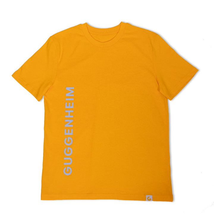 The Guggenheim Constellation T-Shirt in New York Yellow is an organic cotton crewneck featuring "GUGGENHEIM" printed vertically in white on the left side, with a small white tag at the bottom right for an artful finish.