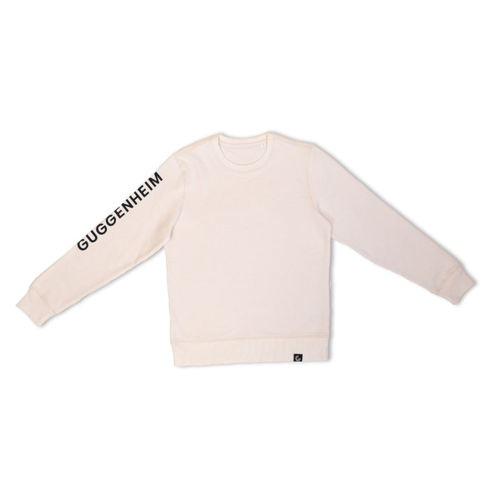 The Guggenheim Constellation Crewneck Sweatshirt in New York Natural, made from organic cotton, displays "GUGGENHEIM" in bold black on the left sleeve and is shown laid flat against a white background.