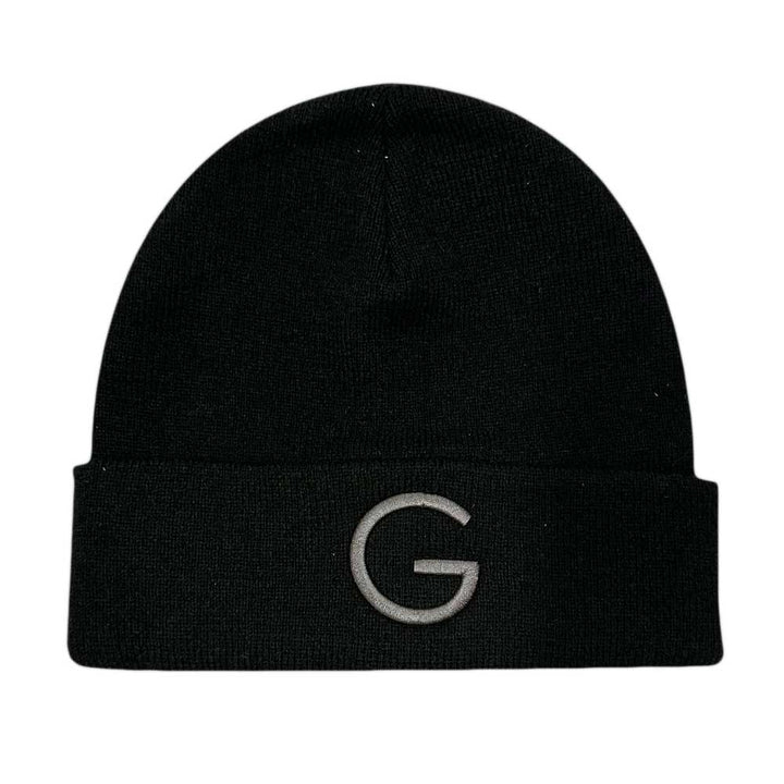 The Guggenheim Going Dark Beanie is a limited edition acrylic knit black beanie with a folded brim, featuring a large gray embroidered G on the front, shown against a plain white background.