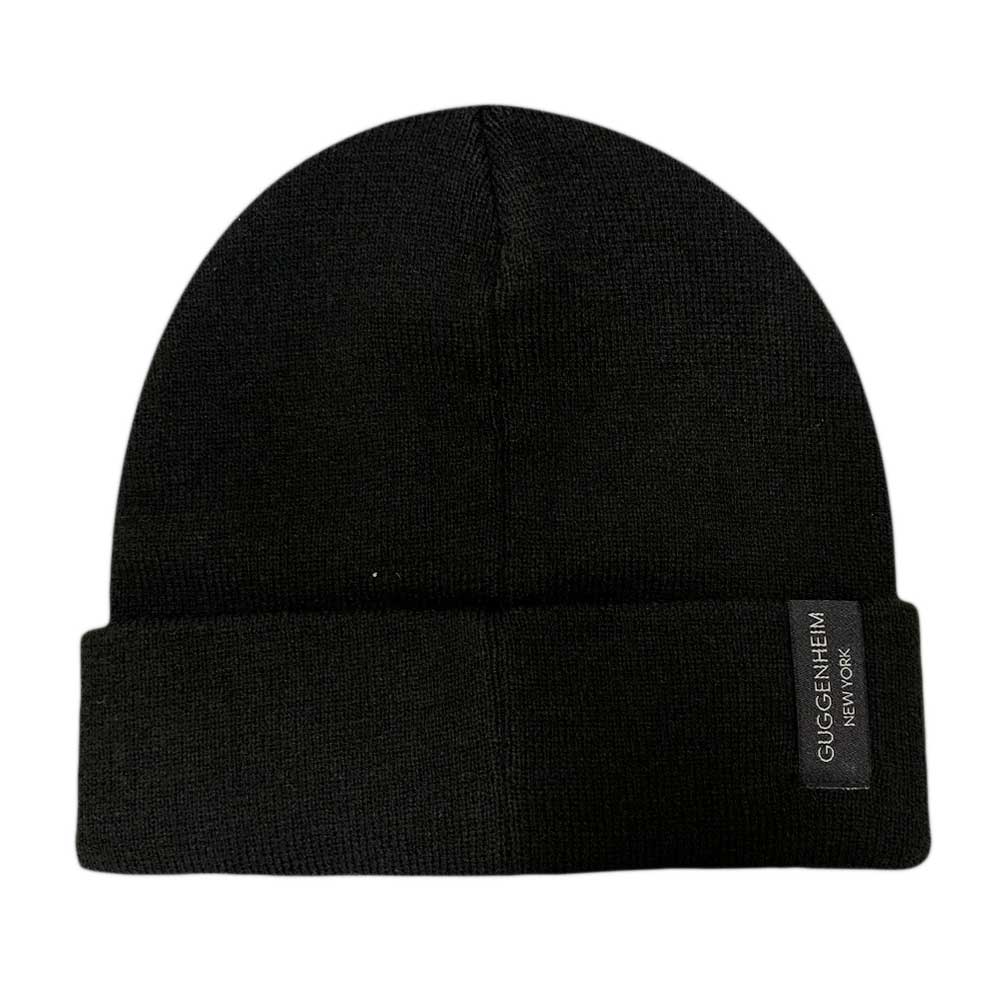 The Guggenheim Going Dark Beanie is a limited edition black acrylic knit hat with a folded brim and a black label reading "Guggenheim New York" in white text—part of the exclusive Going Dark collection.