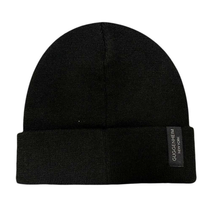 The Guggenheim Going Dark Beanie is a limited edition black acrylic knit hat with a folded brim and a black label reading "Guggenheim New York" in white text—part of the exclusive Going Dark collection.
